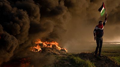 فلسطينيون يحرقون الإطارات ويلوحون بالعلم خلال احتجاج على الغارة العسكرية الإسرائيلية في مدينة جنين بالضفة الغربية قي 26 يناير 2023