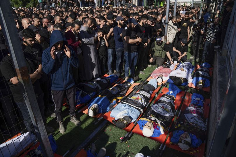 Mourners pray over the bodies of Palestinians, draped in the Islamic Jihad militant group flags, during their funeral in the Nur Shams refugee camp, near the West Bank