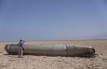 Un fotoreporter osserva una parte del missile balistico intercettato che è caduto vicino al Mar Morto in Israele, domenica 21 aprile 2024