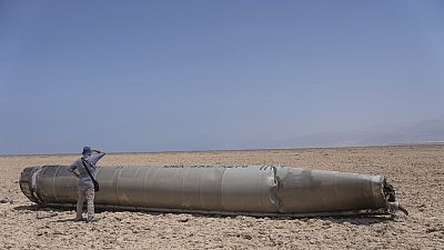 Un fotoreporter osserva una parte del missile balistico intercettato che è caduto vicino al Mar Morto in Israele, domenica 21 aprile 2024