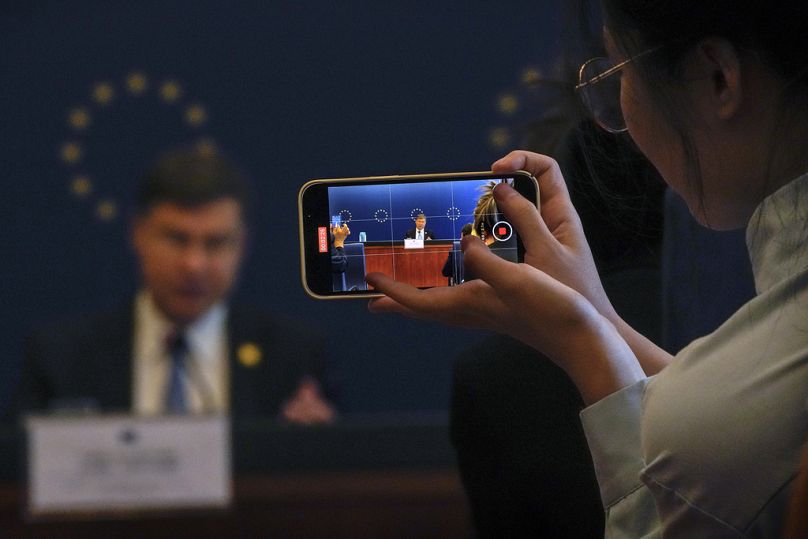 A reporter uses a smartphone to film European Commissioner for Economy and Trade Valdis Dombrovskis speaks during a news conference in Beijing, September 2023
