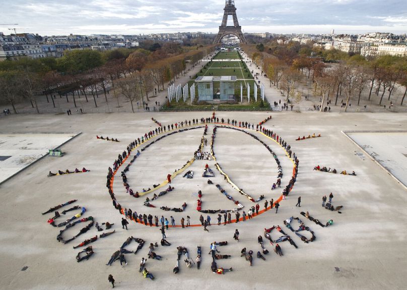 environmentalist activists form a human chain representing the peace sign and the spelling out "100% renewable", on the side line of the COP21 in Paris, December 2015