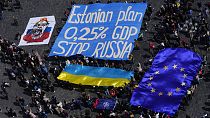 المتجمعون يرفعون لافتة تطالب بتخصيص 0.25% من الناتج القومي لكل دولة لدعم أوكرانيا