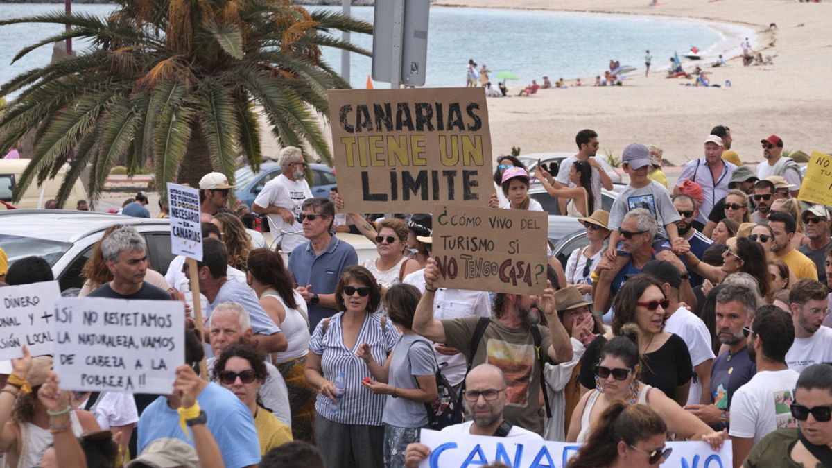 Pessoas marcham junto a uma praia durante uma manifestação contra o turismo excessivo que afecta a população local com habitações inacessíveis, nas Ilhas Canárias.