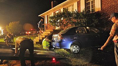 شرطة فريدريكسبيرغ وأفراد إدارة الإطفاء إلى جانب سيارة ارتطمت بمنزل