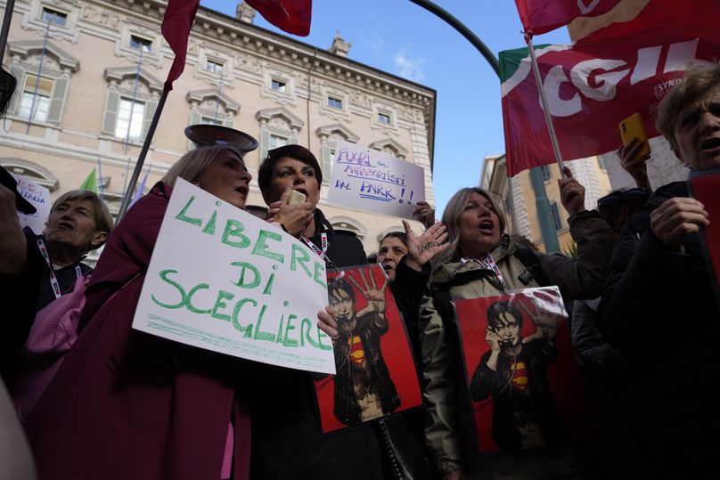Demonstranten zeigen ein Plakat mit der Aufschrift: „Freie Wahl, Abtreibungsgegner raus“vor dem italienischen Senat in Rom, Dienstag, 23. April 2024.