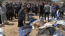 Eine Frau sucht unter den Leichen, die in einem Massengrab in Khan Younis gefunden wurden