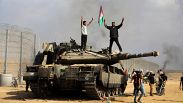 فلسطينيون يحتفلون فوق دبابة إسرائيلية أخذوها كغنيمة عند السياج الفاصل جنوب قطاع غزة يوم7 تشرين الأول / أكتوبر 2023، ضمن عملية "طوفان الأقصى"