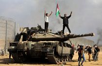 فلسطينيون يحتفلون فوق دبابة إسرائيلية أخذوها كغنيمة عند السياج الفاصل جنوب قطاع غزة يوم7 تشرين الأول / أكتوبر 2023، ضمن عملية "طوفان الأقصى"