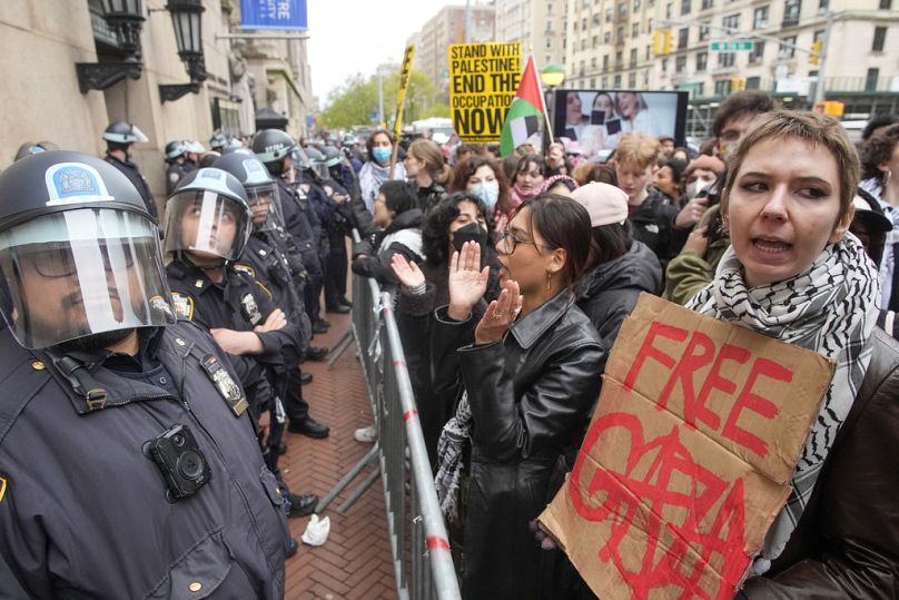 Columbia Üniversitesi kampüsü dışında göstericiler slogan atarken Çevik Kuvvet teçhizatlı polis nöbet tutuyor