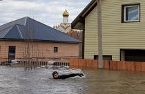 A local resident swims in the flooded street between houses in Orenburg, Russia