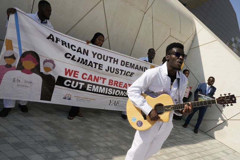 Activists hold a sign reading "African youth climate justice" during a demonstration at the COP28 UN Climate Summit, in Dubai, December 2023