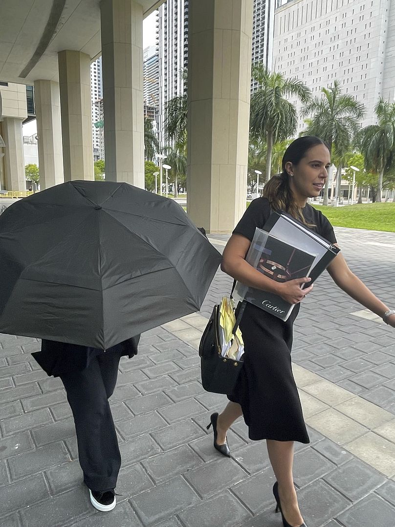 La diseñadora Nancy González, escondida bajo el paraguas, junto a su abogada Andrea López en Miami.