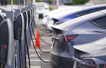 This Aug. 23, 2020 photo shows a long line of unsold 2020 models charge outside a Tesla dealership in Littleton, Colo. 