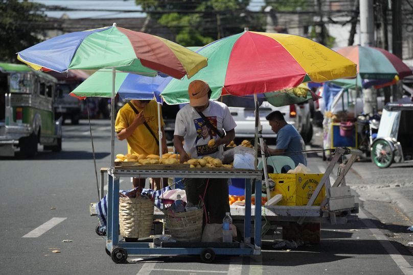 Vendors arrange mangoes under umbrellas to shield them from the scorching sun in Quezon city, Philippines.