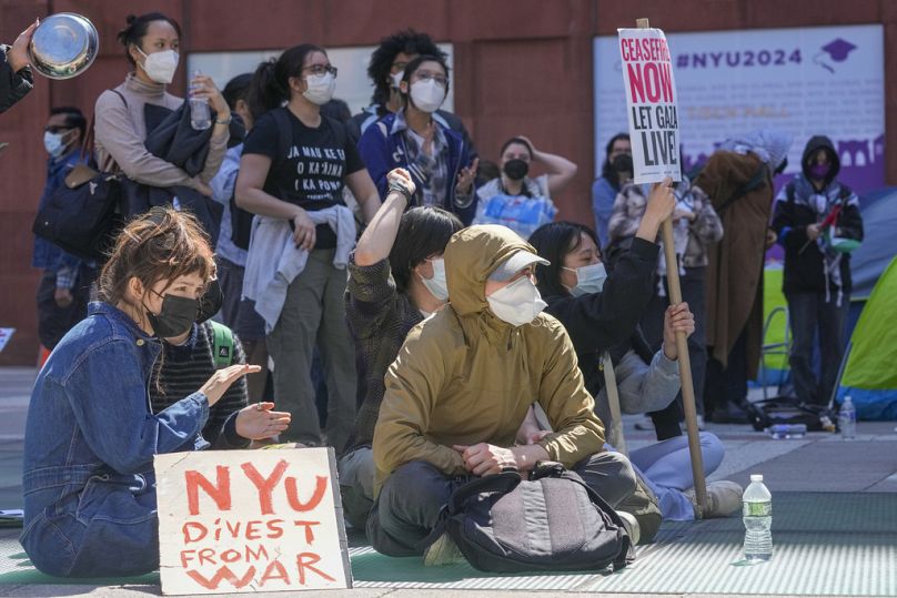 Estudantes da Universidade de Nova Iorque e apoiantes pró-palestinianos manifestam-se em frente ao edifício da NYU Stern School of Business.