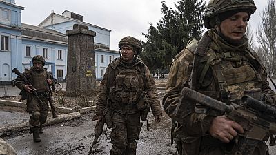 FILE PHOTO - Ukrainian servicemen who recently returned from the trenches of Bakhmut walk on a street in Chasiv Yar, Ukraine, Wednesday, March 8, 2023.