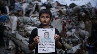 A family member holds a picture of a garment worker, victim of the 2013 Rana Plaza factory collapse