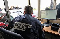Ein französischer Polizist überprüft Pässe und Fahrzeuge am Eingang des Kanaltunnels in Calais, Nordfrankreich