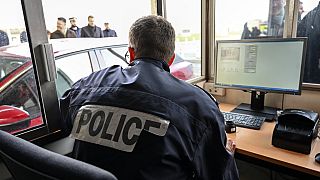 Un agente di polizia francese controlla i passaporti e i veicoli all'ingresso del tunnel della Manica a Calais, nel nord della Francia