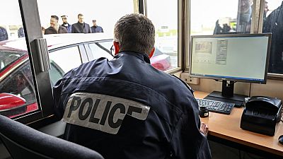 Ein französischer Polizist überprüft Pässe und Fahrzeuge am Eingang des Kanaltunnels in Calais, Nordfrankreich