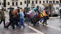 A porter carries tourists luggages outside the main train station in Venice, Italy, Wednesday, April 24, 2024