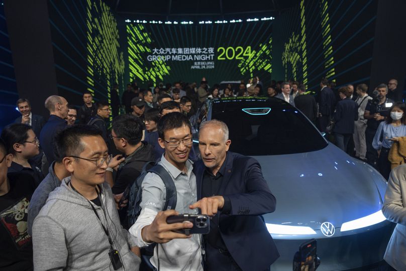 Attendees pose for photos near the latest cars unveiled during a media event held by the Volkswagen Group at the Beijing auto show.