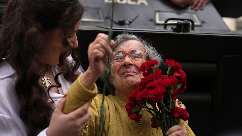 شهروند سالخورده پرتغالی که به نشانه گرامیداشت انقلاب کشورش به خیابان آمده و گل میخک به افسران ارتش هدیه می‌کند