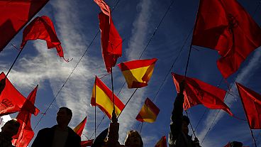 Manifestantes agitam bandeiras espanholas e de Navarra enquanto protestam contra a amnistia na praça Plaza del Castillo, em Pamplona, norte de Espanha, sábado, 18 de novembro de 2023. 