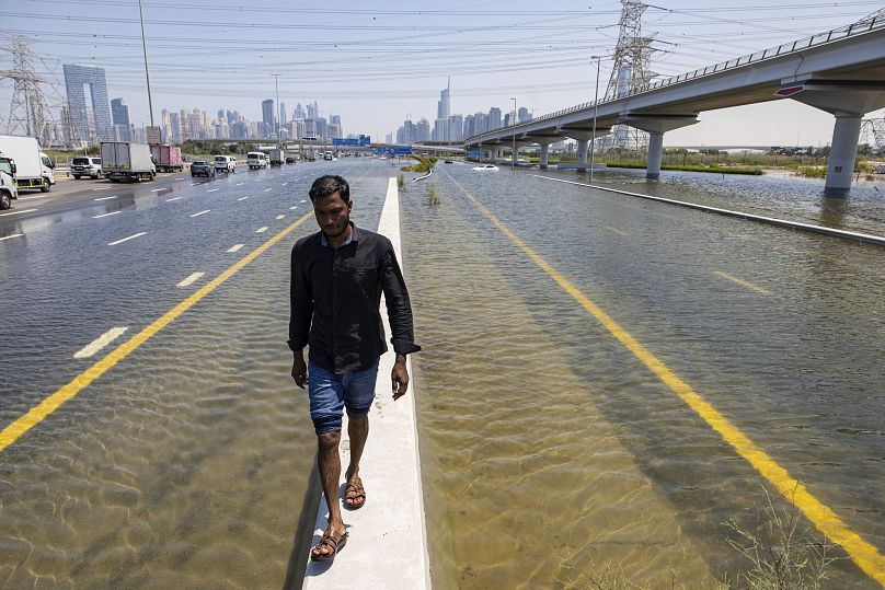A man walks along a road barrier among floodwater caused by heavy rain on Sheikh Zayed Road highway in Dubai.