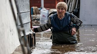 Žena hoda blizu svoje kuće u poplavljenom području u Orenburgu, Rusija, 10. travnja 2024.