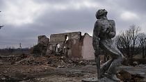 Sowjetisches Denkmal, das den Soldaten des Zweiten Weltkriegs gewidmet ist, vor einem zerstörten Kulturhaus in der Nähe von  Awdijiwka. 21. März 2024