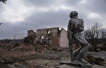 Sowjetisches Denkmal, das den Soldaten des Zweiten Weltkriegs gewidmet ist, vor einem zerstörten Kulturhaus in der Nähe von  Awdijiwka. 21. März 2024