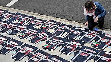 A demonstrator lays candles on the ground next to press vest covered in red paint during a pro-Palestinian protest over the Israel-Hamas war on Saturday April 27, 2024,