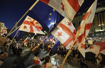 Göstericiler 17 Nisan 2024'te Tiflis'teki parlamento binasının önünde toplanırken Gürcistan ve AB bayraklarını sallıyor