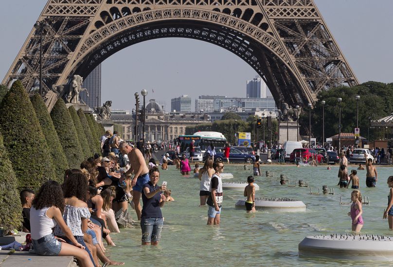 La gente se refresca cerca de la Torre Eiffel en París.