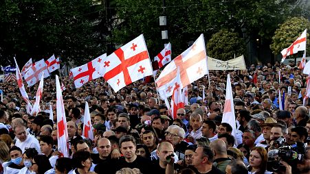 Kormánypárti tüntetők grúz nemzeti zászlóval az „ügynöktörvényt" támogató gyűlésen Tbilisziben, 2024. április 29-én.