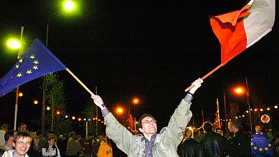 Piotr Zubrzycki waves a Polish, right, and a EU flag to celebrate the EU enlargement 