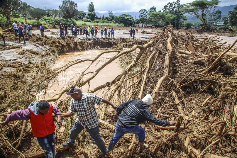 Des personnes tentent de déblayer la zone après la rupture d'un barrage, dans le village de Kamuchiri