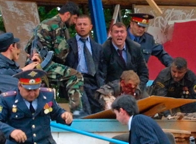 Biztonságiak próbálják felemelni Ahmed Kadirov testét a robbanás után a grozniji Dinamo stadionban, 2004. május 9-én