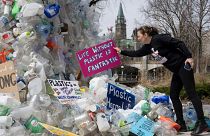 Activist Dianne Peterson places a sign on an art installation outside a United Nations conference on plastics.