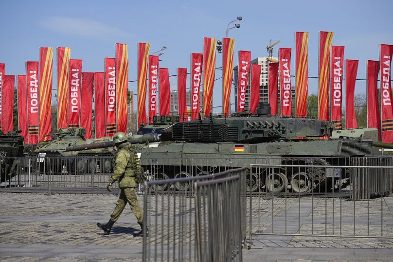 A Russian soldier walks past a Leopard 2A6 tank that belonged to the Ukrainian army is seen on display in Moscow. Tuesday, 30 April 2024.
