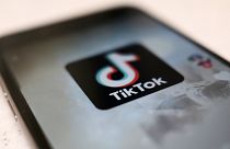 Um logótipo de uma aplicação para smartphone TikTok é visto numa publicação de utilizador no ecrã de um smartphone