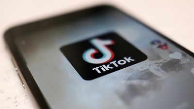 Логотип приложения для смартфонов TikTok виден в посте пользователя на экране смартфона