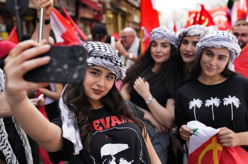 Supporters of the Lebanese Communist party take a selfie, as they march during a demonstration to mark International Labor Day or May Day, in Beirut, Wednesday, May 1, 2024