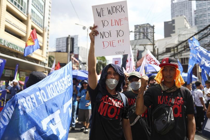 A man carries a poster during a protest to mark International Labor Day near the presidential palace in Manila, Philippines on Wednesday, May 1, 2024.