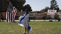 Φιλοϊσραηλινός διαδηλωτής και στο βάθος πανό υπέρη της Παλαιστίνης