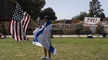 A pro-Israel supporter walks with an American flag near the pro-Palestinian encampment on UCLA campus (AP Photo/Jae C. Hong)