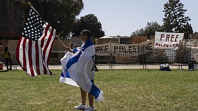 A pro-Israel supporter walks with an American flag near the pro-Palestinian encampment on UCLA campus (AP Photo/Jae C. Hong)