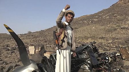 a Houthi fighter celebrates in front of what they said debris of an American MQ9 aerial vehicle, shot down by the air defence in Saada, 26 April 2024